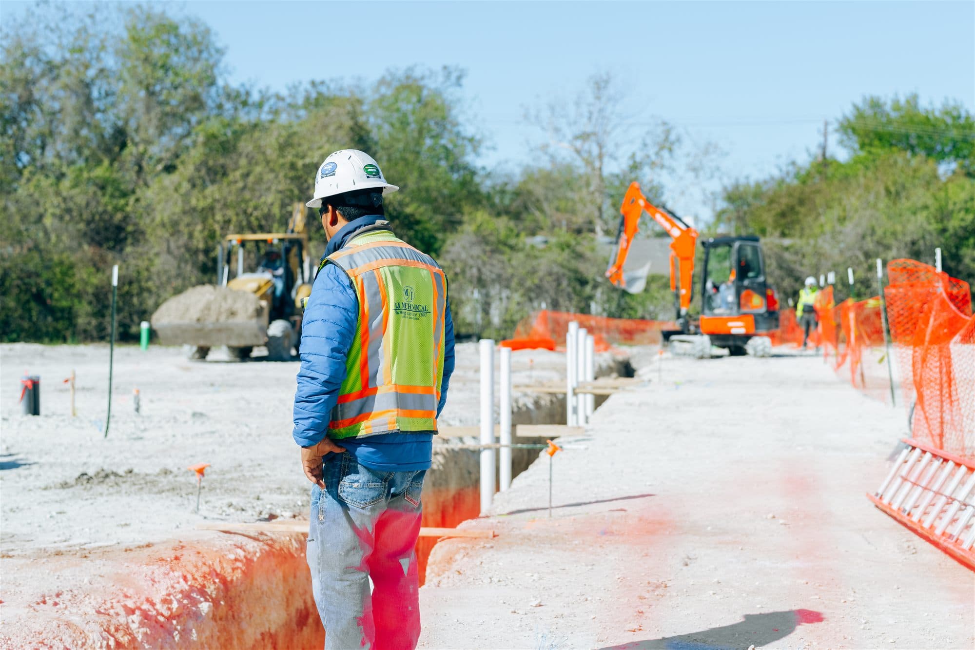 MJ Mechanical crew member walking the trench line on a commercial site